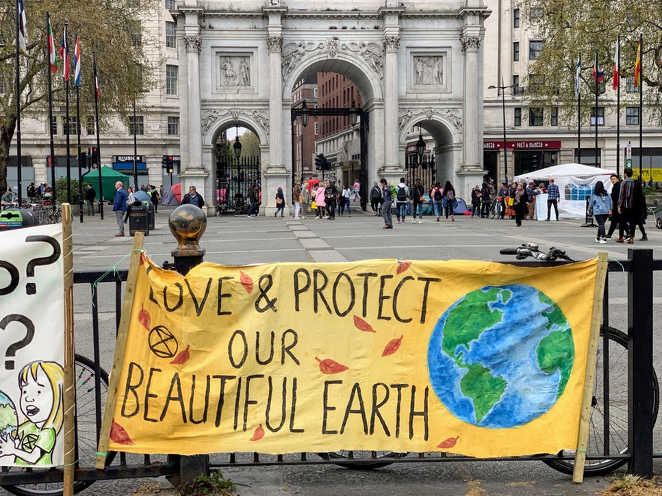 climate protest in Paris, sign over railing reading: Love & Protect our Beautiful Earth